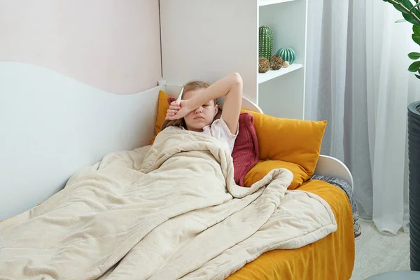 Malato preteen ragazza posa in letto utilizzando termometro — Foto Stock