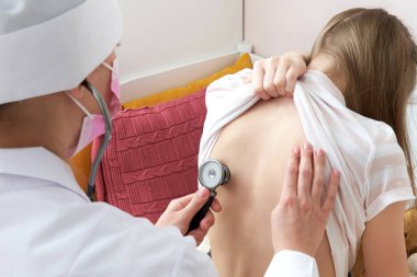 Doktor, evde steteskop, tıp ve sağlık hizmetleri kavramlarıyla kızı muayene ediyor.