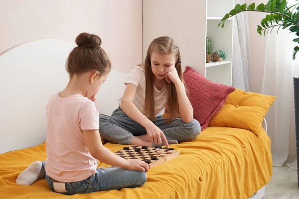 Zwei Schwestern, die Checker spielen, auf einem schlechten Spaß zu Hause, glückliche Kinder Konzept — Stockfoto