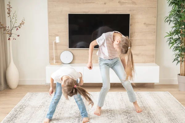 Due sorelle che si divertono a ballare in salotto, concetto di famiglia felice — Foto Stock