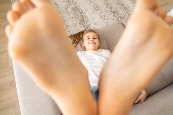 Preteen girl liegend auf couch mit ihren nackten füßen hochheben — Stockfoto