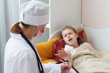 Doktor hasta küçük kızı evde ziyaret ediyor ve reçete yazıyor. 