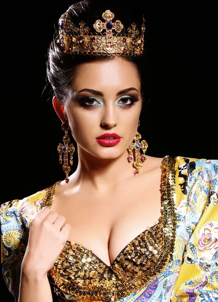 woman with dark  hair in luxurious gold dress with bijou and crown,