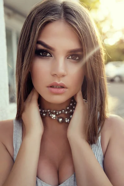 Hermosa chica con cabello oscuro y maquillaje brillante en vestido elegante y collar — Foto de Stock