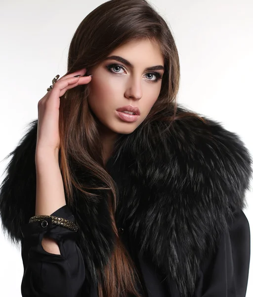 woman with long dark hair in elegant dress, fur coat and accessories
