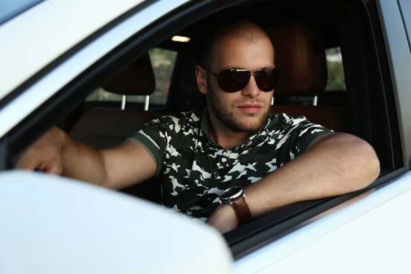 Yakışıklı adam arabanın içinde poz güneş gözlüğü — Stok fotoğraf