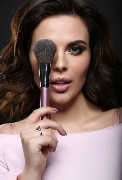 Gorgeous woman with dark hair finishing her makeup using powder — Stock Photo, Image