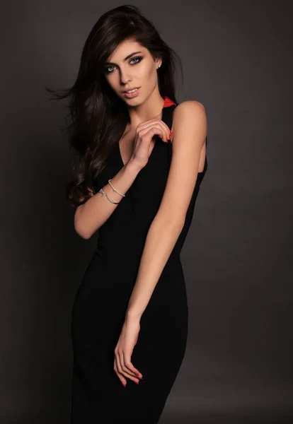 Gorgeous woman with long dark hair posing in studio in black dre — Stock Photo, Image