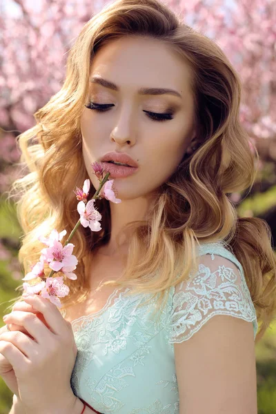 Splendida donna con i capelli biondi in abito elegante in posa in fiore — Foto Stock