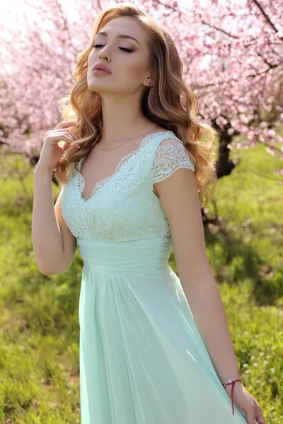 Blosso içinde poz şık elbiseli sarışın saçlı güzel kadın — Stok fotoğraf