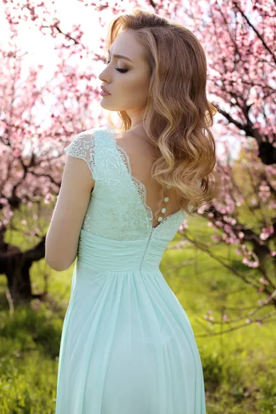 Prachtige vrouw met blond haar in elegante jurk poseren in blosso — Stockfoto