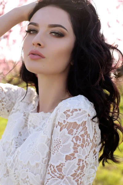 Mujer con el pelo oscuro en vestido elegante posando en el jardín de flores —  Fotos de Stock