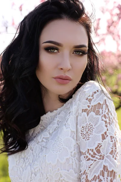 Mujer con el pelo oscuro en vestido elegante posando en el jardín de flores — Foto de Stock