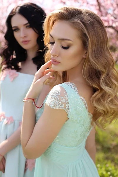 Belle donne in abiti eleganti in posa in giardino fiorito — Foto Stock