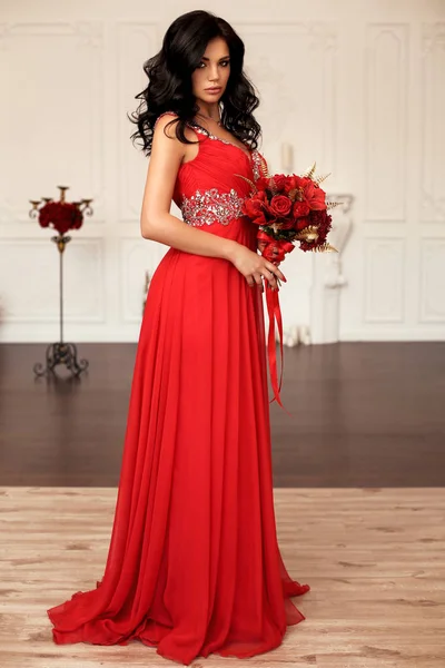 Krásná mladá žena s tmavými vlasy v luxusní červené šaty — Stock fotografie