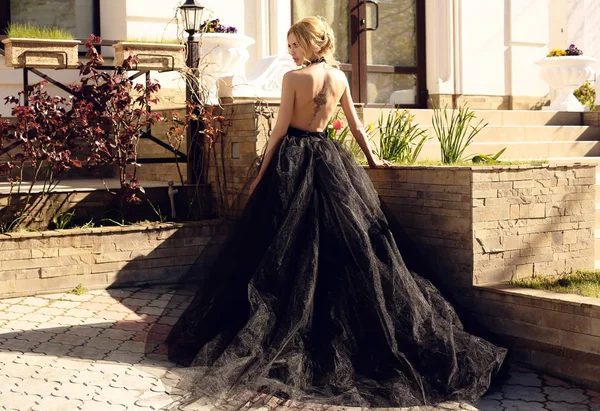 Beautiful girl with blond hair in luxurious black dress — Stock Photo, Image