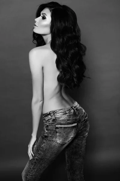 Hermosa mujer sexy con cabello oscuro en jeans posando en el estudio —  Fotos de Stock