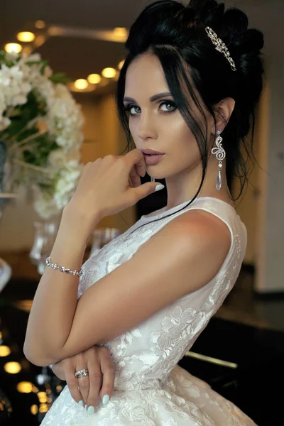 Wunderschöne Braut mit dunklen Haaren in luxuriösem Brautkleid und Accessoires — Stockfoto