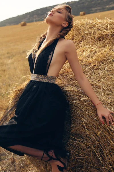 Girl with blond hair in elegant dress posing on the hay — Stock Photo, Image