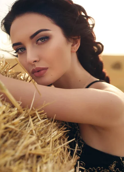 Menina com cabelo escuro em vestido elegante posando no feno — Fotografia de Stock