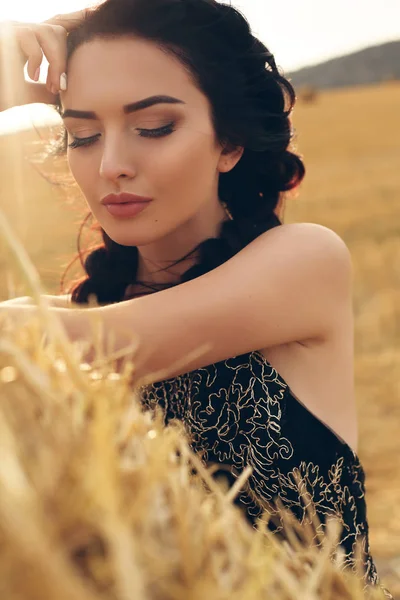 Meisje met donkere haren in elegante jurk poseren op het hooi — Stockfoto