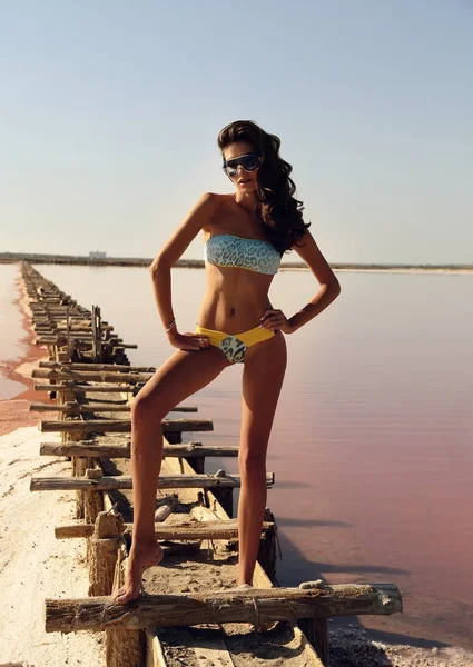 Beautiful girl with dark hair in elegant swimsuit posing near re — Stock Photo, Image