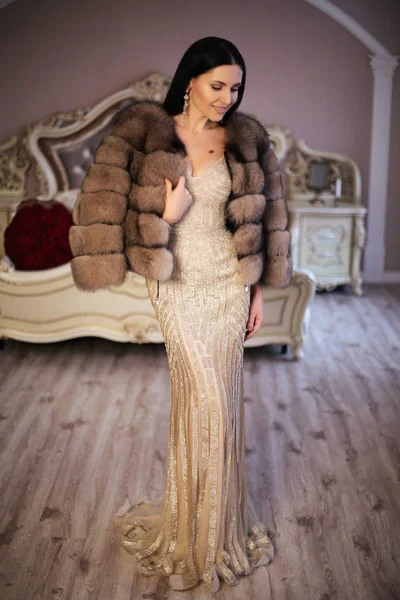 Gorgeous woman with dark hair in luxurious dress and fur coat — Stock Photo, Image