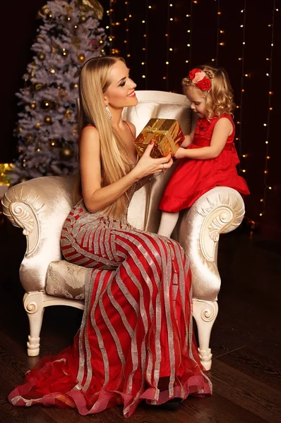 Beautiful mother and daughter posing near Christmas tree at home — Stock Photo, Image