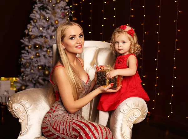 Beautiful mother and daughter posing near Christmas tree at home — Stock Photo, Image