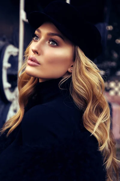 Mooi meisje met blond krullend haar in elegante jas en hoed — Stockfoto