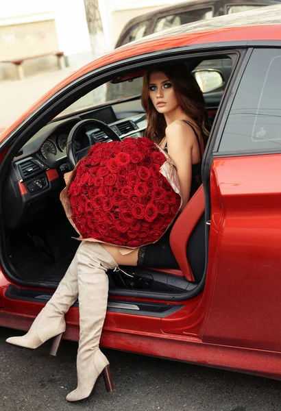 Bella ragazza in abito elegante in posa in auto di lusso con bo — Foto Stock