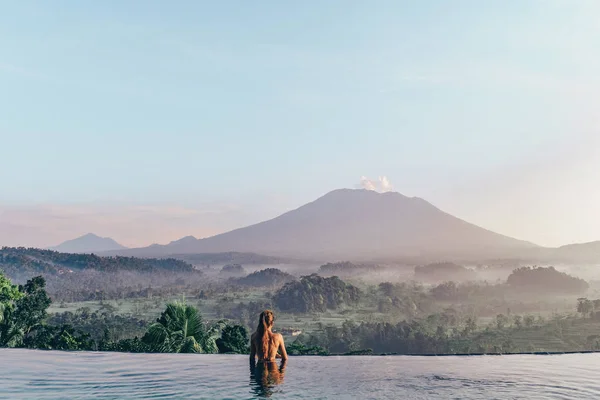 Schönes Mädchen in der Nähe von Schwimmbad mit fantastischem Vulkan — Stockfoto