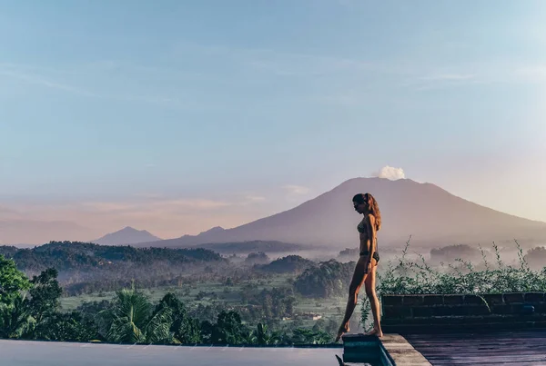 Schönes Mädchen in der Nähe von Schwimmbad mit fantastischem Vulkan — Stockfoto