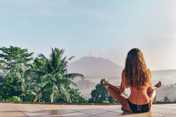 Beautiful girl is meditating on terrace with a stanning view on — Stock Photo, Image