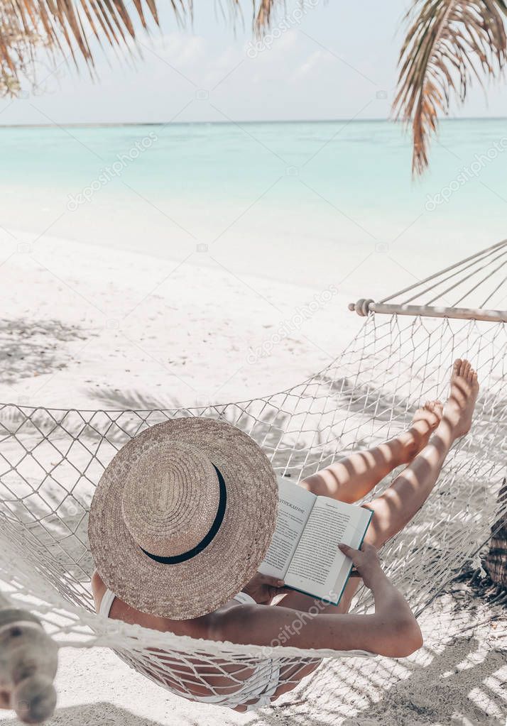 Travel series. Maldive islands. girl is relaxing in hammock and reading book