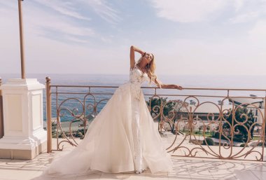 lüks düğün elbise ve aksesuarlar deniz ve dağ manzaralı açık poz sarışın saçlı güzel şehvetli kadın moda fotoğrafı