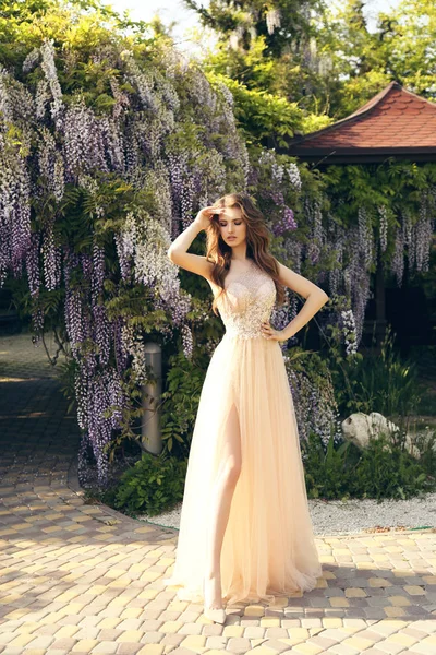 Nő, hosszú haj, luxus ruhában pózol között virágzó w — Stock Fotó