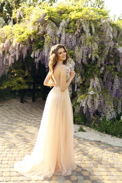 Femme avec les cheveux longs en robe de luxe posant parmi la floraison w — Photo