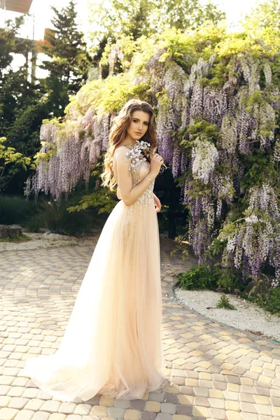 Woman with long hair in luxurious dress posing among flowering w — Stock Photo, Image