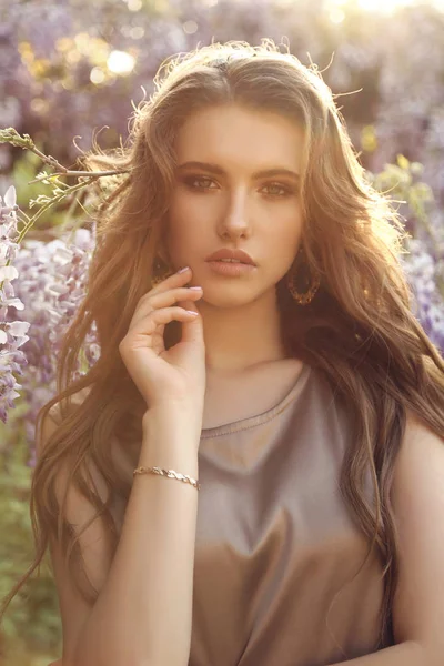 Woman with long hair in luxurious dress posing among flowering w — Stock Photo, Image