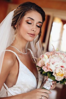 Şık gelinlik içinde güzel, mutlu bir gelin ve bir buket f