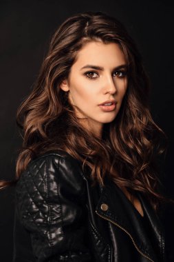 Stüdyoda poz veren zarif deri ceketli güzel seksi kadın.