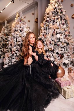 Şık elbiseli, kızıl saçlı güzel bir kadın onunla poz veriyor.