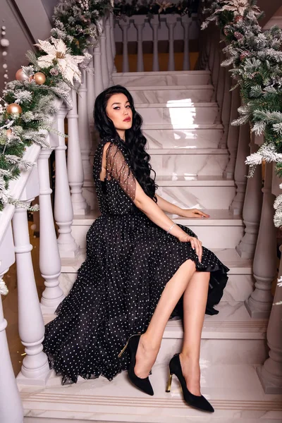 Schöne Mädchen mit dunklen Haaren in elegantem Kleid posiert in Dekoration — Stockfoto