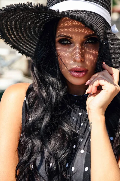 Beautiful woman with dark hair in elegant dress and hat — Stockfoto