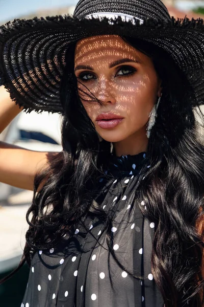 Beautiful woman with dark hair in elegant dress and hat — Stockfoto