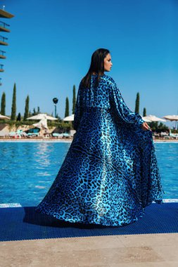 Şık yüzme takımlı, güzel, şehvetli bir kadının yüzme havuzunun yanında dinlenirken çekilmiş moda fotoğrafı.