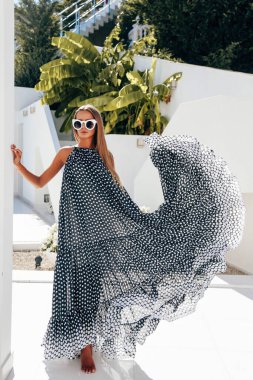 Uzun sarı saçlı, zarif mayolu ve aksesuarlı güzel seksi bir kadının lüks beyaz villada rahatlatıcı aksesuarları.