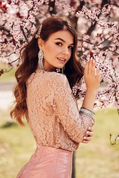 在公园里 穿着雅致衣服 一头乌黑的秀发 站在开满鲜花的桃树中间的美丽女子的时尚照片 — 图库照片
