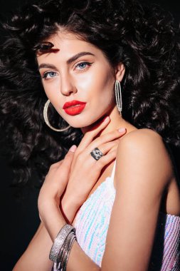 Güzel, kıvırcık saçlı, aksesuarlı, zarif elbiseli seksi bir kadının moda stüdyosu fotoğrafı.